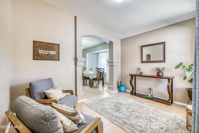 living area featuring arched walkways, a textured ceiling, baseboards, and tile patterned flooring