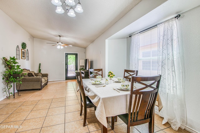dining room featuring ceiling fan with notable chandelier, light tile patterned flooring, baseboards, and vaulted ceiling