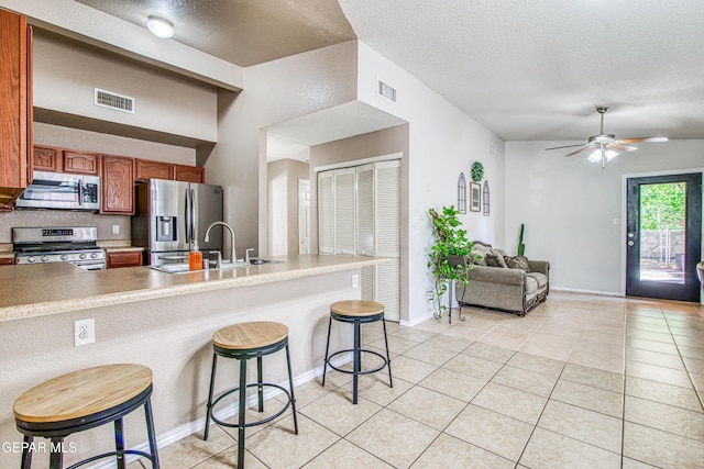 kitchen featuring brown cabinets, visible vents, a kitchen breakfast bar, and stainless steel appliances