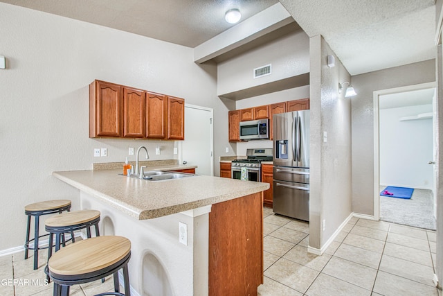 kitchen featuring visible vents, appliances with stainless steel finishes, light countertops, a sink, and baseboards