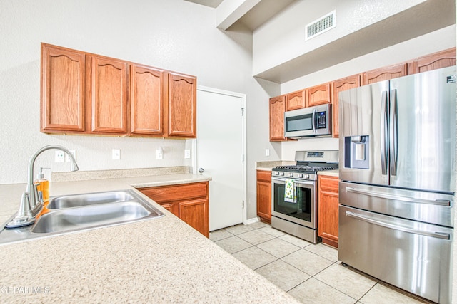 kitchen with visible vents, appliances with stainless steel finishes, light tile patterned flooring, light countertops, and a sink