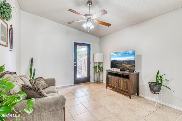 living area featuring baseboards, a textured ceiling, a ceiling fan, light tile patterned flooring, and lofted ceiling
