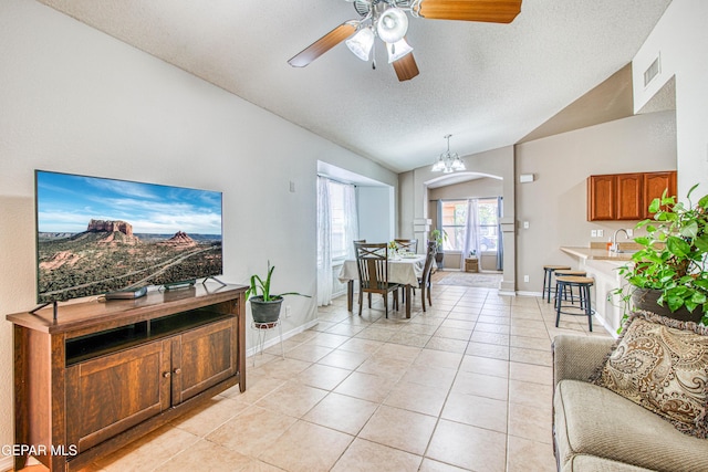 living room featuring visible vents, ceiling fan, a textured ceiling, vaulted ceiling, and light tile patterned flooring
