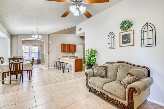 living room featuring light tile patterned floors, visible vents, a textured ceiling, and lofted ceiling
