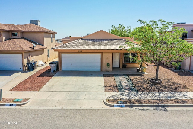 view of front of house featuring a tiled roof, driveway, a garage, and stucco siding
