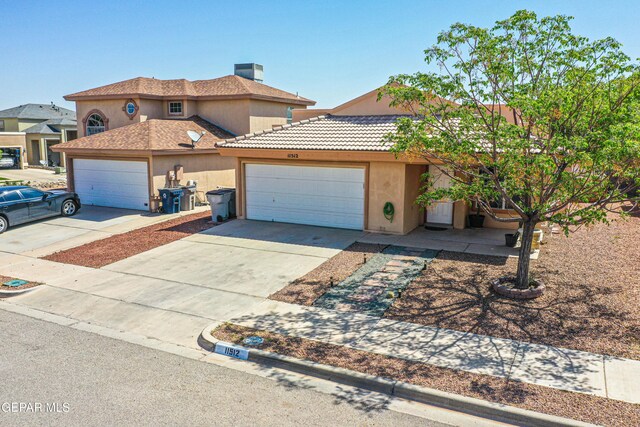 view of front of property with a garage, driveway, a chimney, and stucco siding