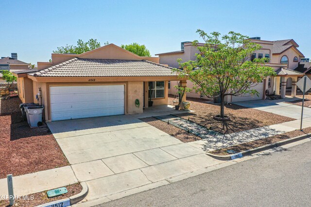 view of front of house with a tile roof, an attached garage, driveway, and stucco siding