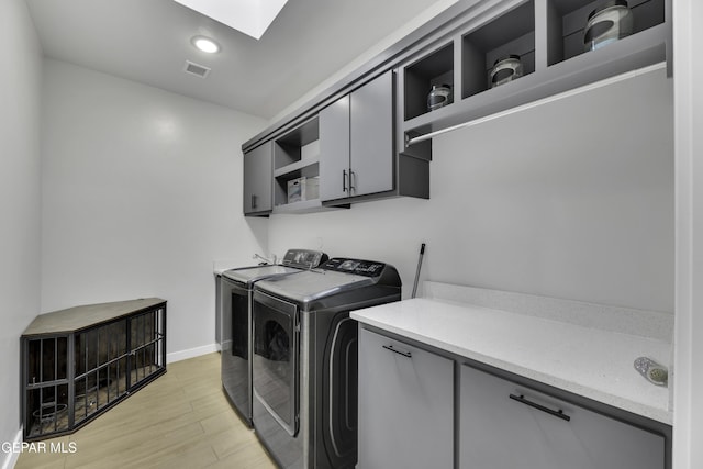 784 Brunswick Pl, Horizon City, TX 79928 - clothes washing area featuring visible vents, washer and dryer, light wood-type flooring, cabinet space, and a skylight