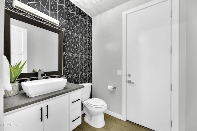 784 Brunswick Pl, Horizon City, TX 79928 - half bath featuring an accent wall, toilet, vanity, wood finished floors, and wallpapered walls