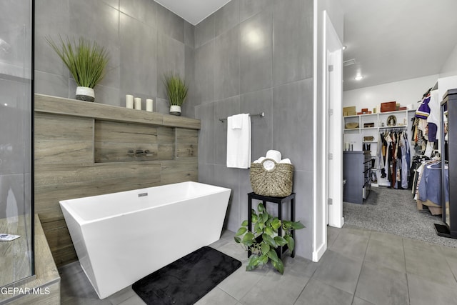 784 Brunswick Pl, Horizon City, TX 79928 - full bathroom with a freestanding bath, tile patterned flooring, a walk in closet, and tile walls
