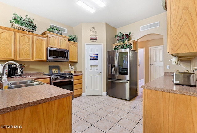 kitchen with visible vents, light tile patterned floors, arched walkways, a sink, and appliances with stainless steel finishes