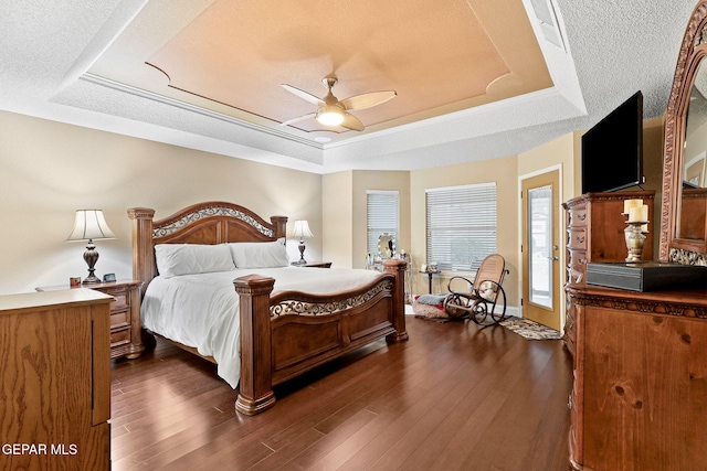 bedroom with a tray ceiling, a ceiling fan, dark wood-style floors, and baseboards