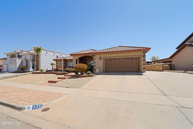 mediterranean / spanish-style house featuring a tile roof, an attached garage, driveway, and stucco siding