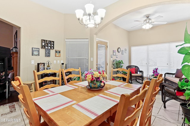 dining area with arched walkways, ceiling fan with notable chandelier, and light tile patterned floors