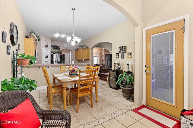 dining room with light tile patterned floors, arched walkways, and an inviting chandelier