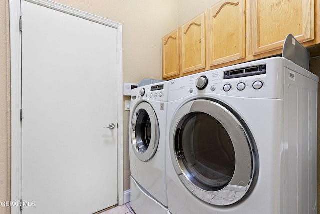clothes washing area featuring light tile patterned floors, independent washer and dryer, and cabinet space