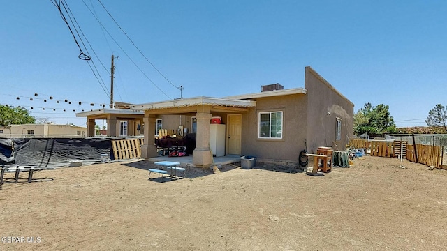 view of front of home with a patio area, stucco siding, and fence