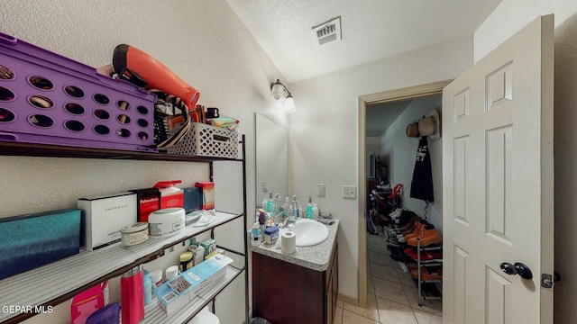 bathroom featuring visible vents, a textured ceiling, vanity, tile patterned floors, and lofted ceiling