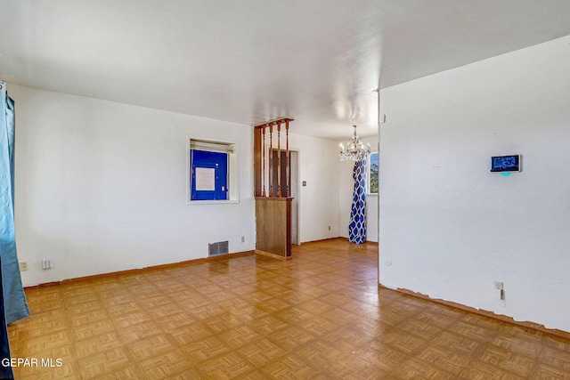 empty room with visible vents, baseboards, and a chandelier