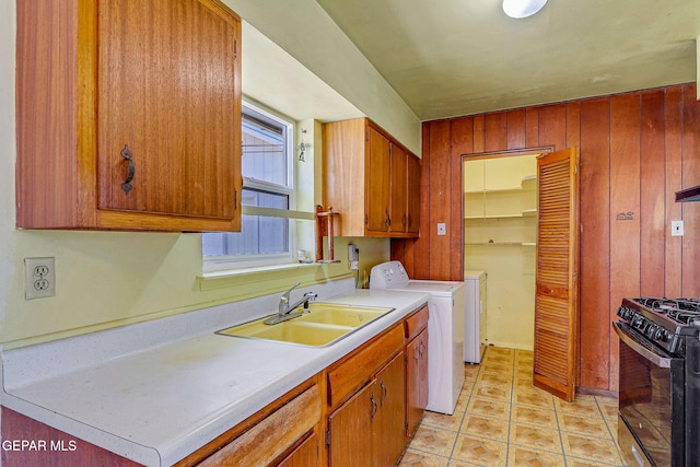clothes washing area featuring a sink, independent washer and dryer, laundry area, and wooden walls