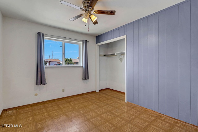 unfurnished bedroom featuring a closet, wood walls, and a ceiling fan
