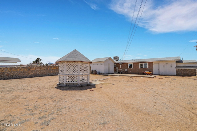 rear view of house featuring a gazebo, cooling unit, and fence