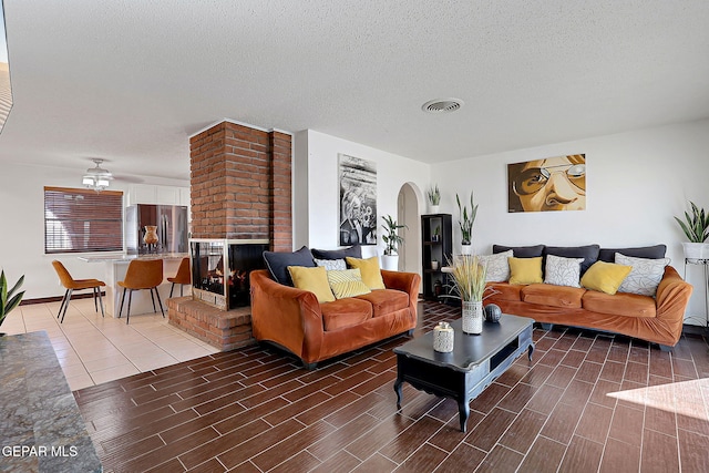 3705 Roslyn Dr, Horizon City, TX 79928 - living area featuring ceiling fan, visible vents, a brick fireplace, wood finished floors, and arched walkways