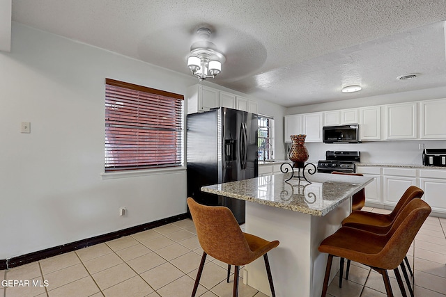 3705 Roslyn Dr, Horizon City, TX 79928 - kitchen with a breakfast bar, white cabinetry, black appliances, and light tile patterned floors