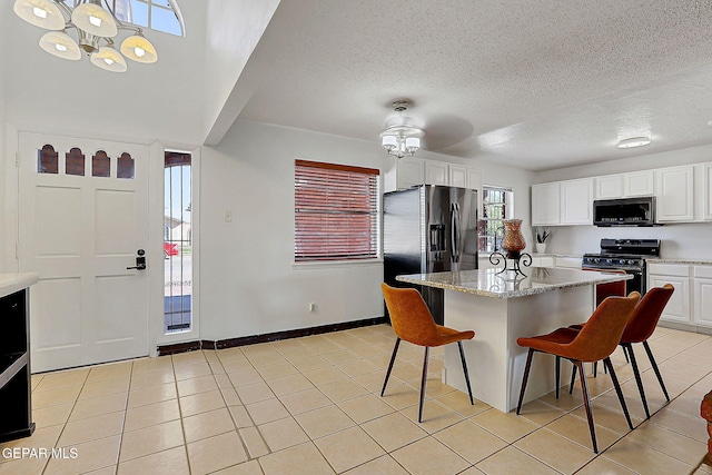 3705 Roslyn Dr, Horizon City, TX 79928 - kitchen featuring white cabinets, stainless steel appliances, light tile patterned flooring, and a kitchen breakfast bar