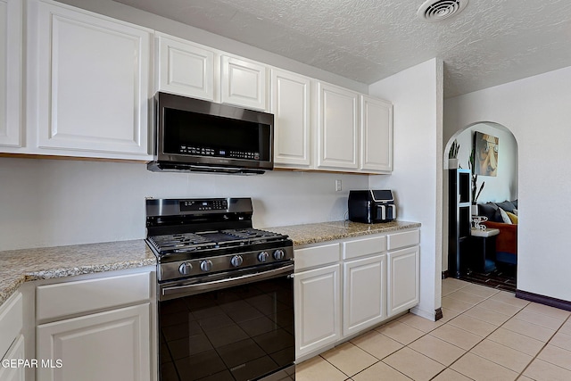 3705 Roslyn Dr, Horizon City, TX 79928 - kitchen with visible vents, arched walkways, light tile patterned floors, white cabinets, and appliances with stainless steel finishes