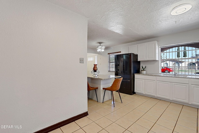 3705 Roslyn Dr, Horizon City, TX 79928 - kitchen with black refrigerator with ice dispenser, light stone countertops, a textured ceiling, a sink, and white cabinets