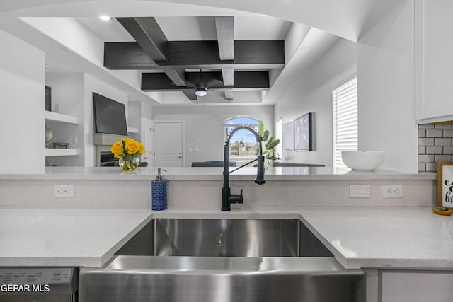 kitchen with a sink, a ceiling fan, beamed ceiling, stainless steel dishwasher, and coffered ceiling