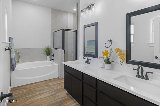 bathroom with a tile shower, double vanity, a bath, and a sink