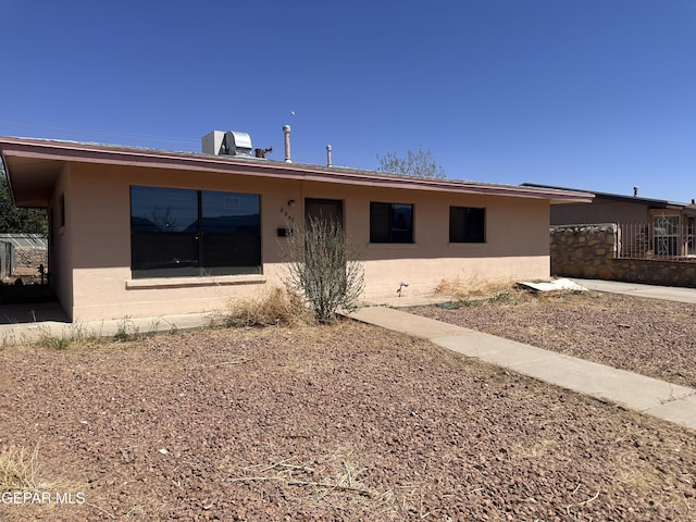 ranch-style house featuring stucco siding and fence