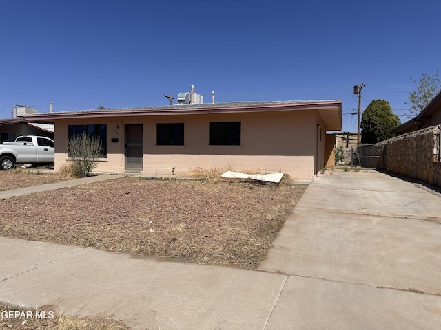 view of front of home with concrete driveway, stucco siding, and fence