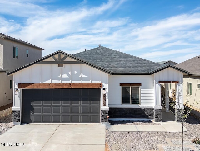 view of front of home with concrete driveway, a shingled roof, stone siding, and an attached garage