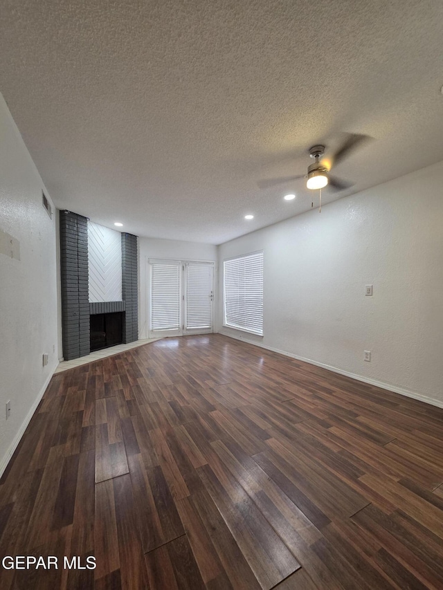 425 Irondale Dr Unit E, El Paso, TX 79912 - unfurnished living room with wood finished floors, a textured ceiling, a ceiling fan, baseboards, and a fireplace