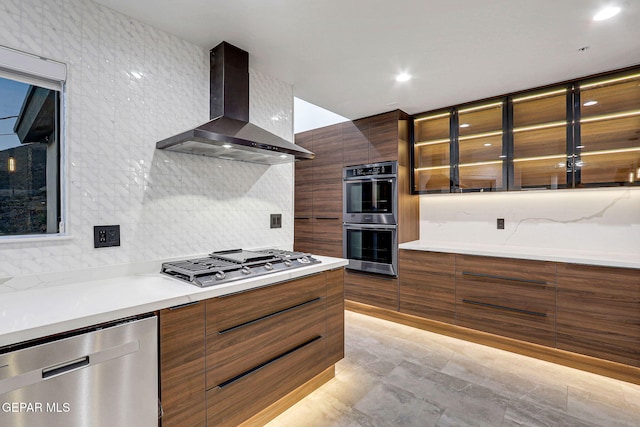 4108 Metetuye Ln, El Paso, TX 79902 - kitchen featuring wall chimney exhaust hood, modern cabinets, appliances with stainless steel finishes, brown cabinetry, and backsplash