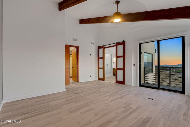 4108 Metetuye Ln, El Paso, TX 79902 - spare room featuring baseboards, a ceiling fan, a barn door, beam ceiling, and light wood finished floors