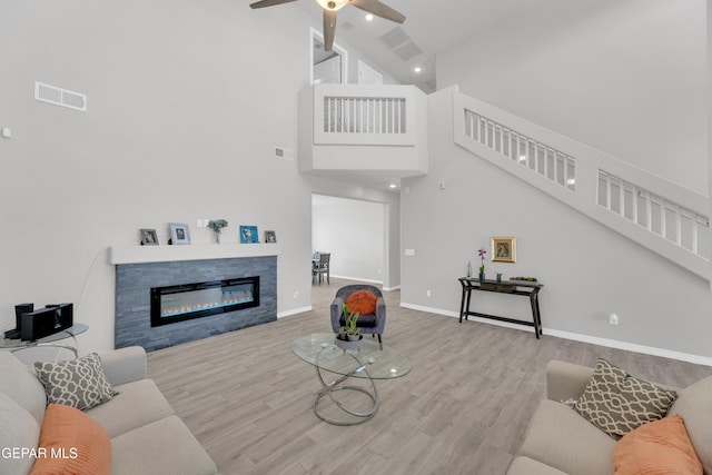 living room featuring high vaulted ceiling, stairs, visible vents, and a ceiling fan