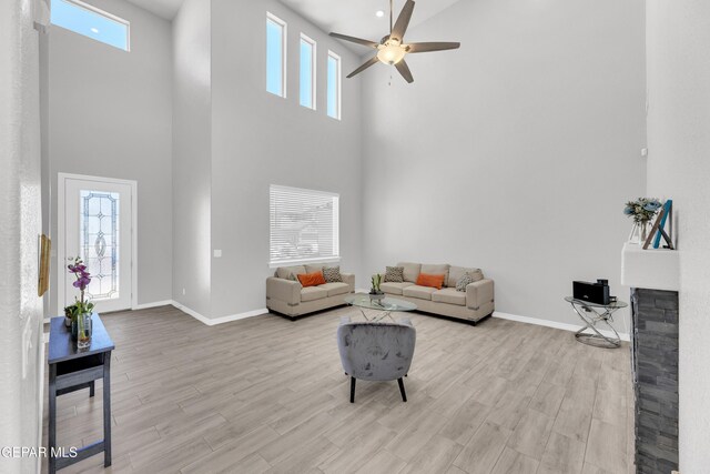 living area with a towering ceiling, baseboards, and ceiling fan