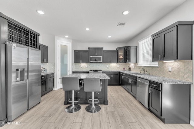 kitchen featuring a kitchen island, light stone countertops, visible vents, and appliances with stainless steel finishes