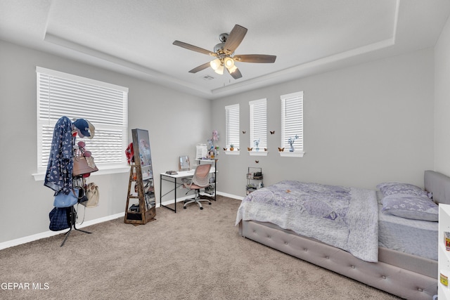 bedroom with baseboards, a raised ceiling, carpet flooring, and a ceiling fan
