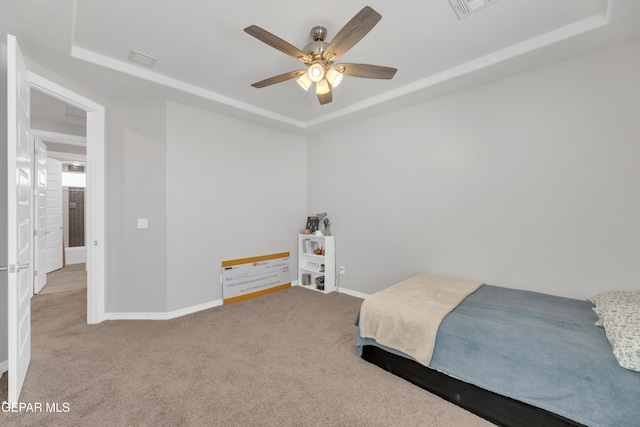 carpeted bedroom with visible vents, a tray ceiling, and baseboards