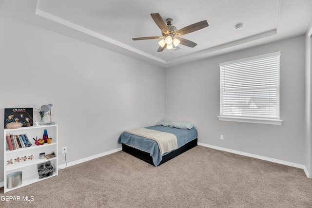 bedroom with baseboards, a raised ceiling, and carpet