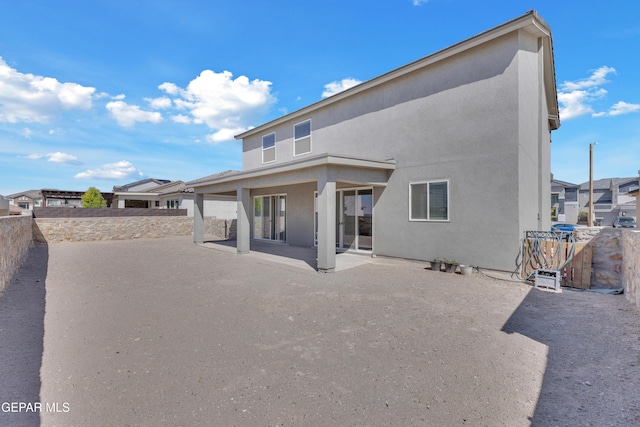 rear view of house featuring a patio area, stucco siding, and a fenced backyard