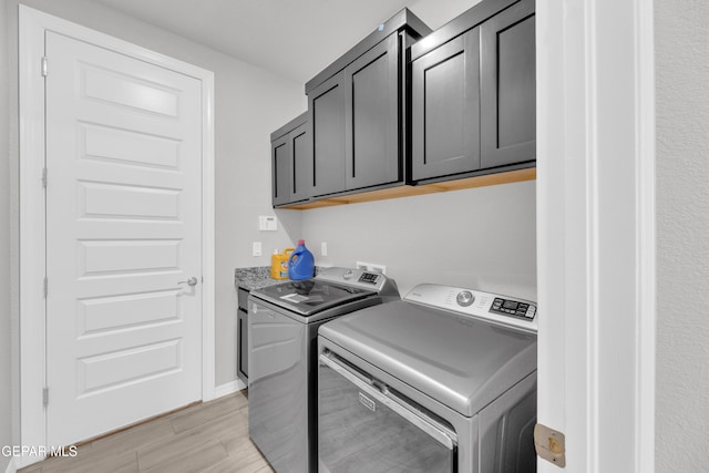 laundry area with baseboards, light wood-type flooring, washing machine and clothes dryer, and cabinet space