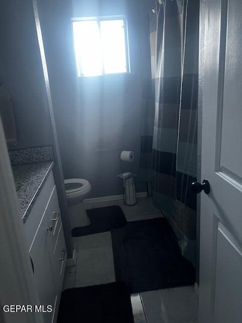 bathroom with toilet, vanity, and tile patterned flooring