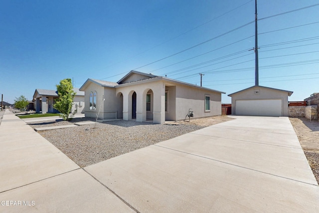 single story home featuring a garage, concrete driveway, stucco siding, and an outbuilding