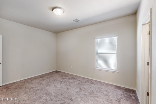 carpeted spare room featuring visible vents and baseboards
